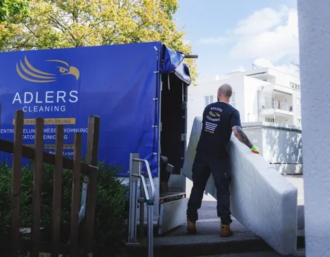 Mitarbeiter belädt den Transporter von Adlers Cleaning mit einer Matratze